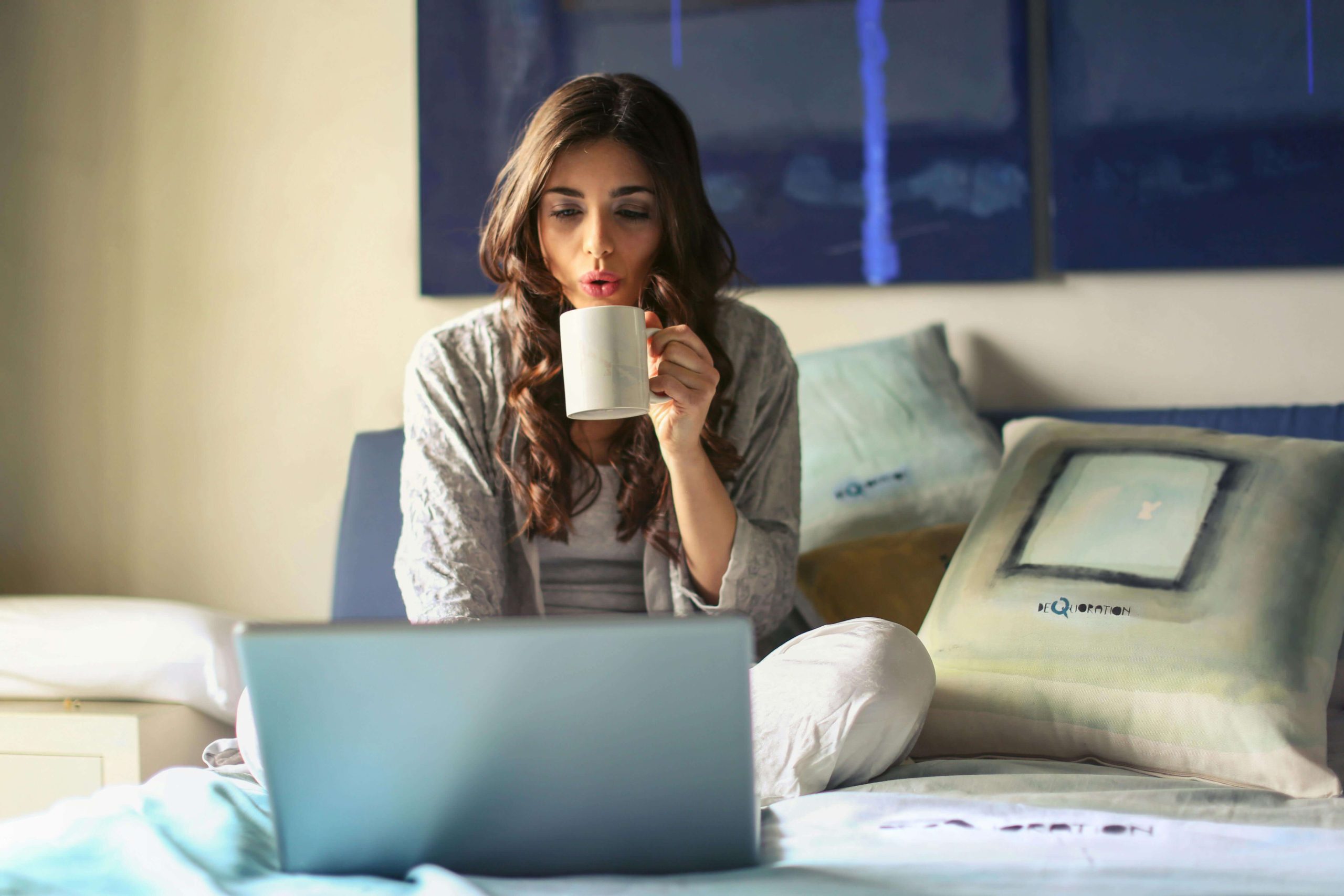 djevojka radi iz kreveta, s laptopom i kavom
